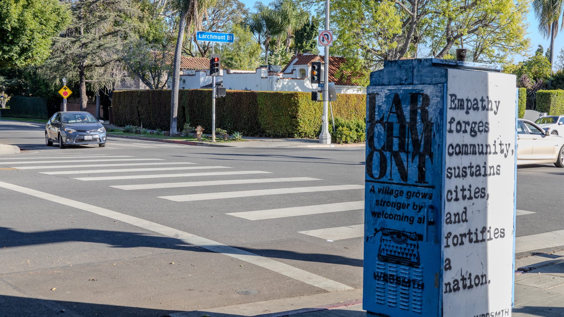 Painted utility box at a Larchmont crosswalk reading "Empathy forges community"