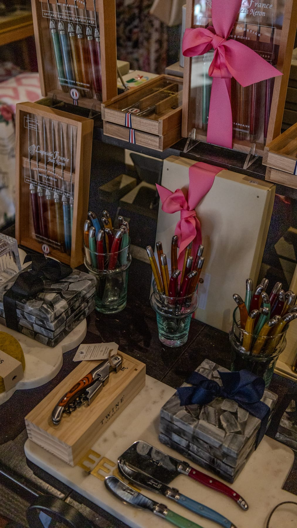 Pens, wine openers and gift boxes with pink ribbon on a Village Heights display table